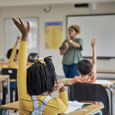 Student raising hand in classroom.