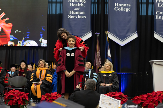 Texas A&M University-Texarkana Provost and Senior Vice President for Academic Affairs Dr. Melinda Arnold places the traditional doctoral hood on Sonja Yates Hubbard. Hubbard was awarded an honorary Doctor of Leadership degree for her decades of service to the Texarkana Community.