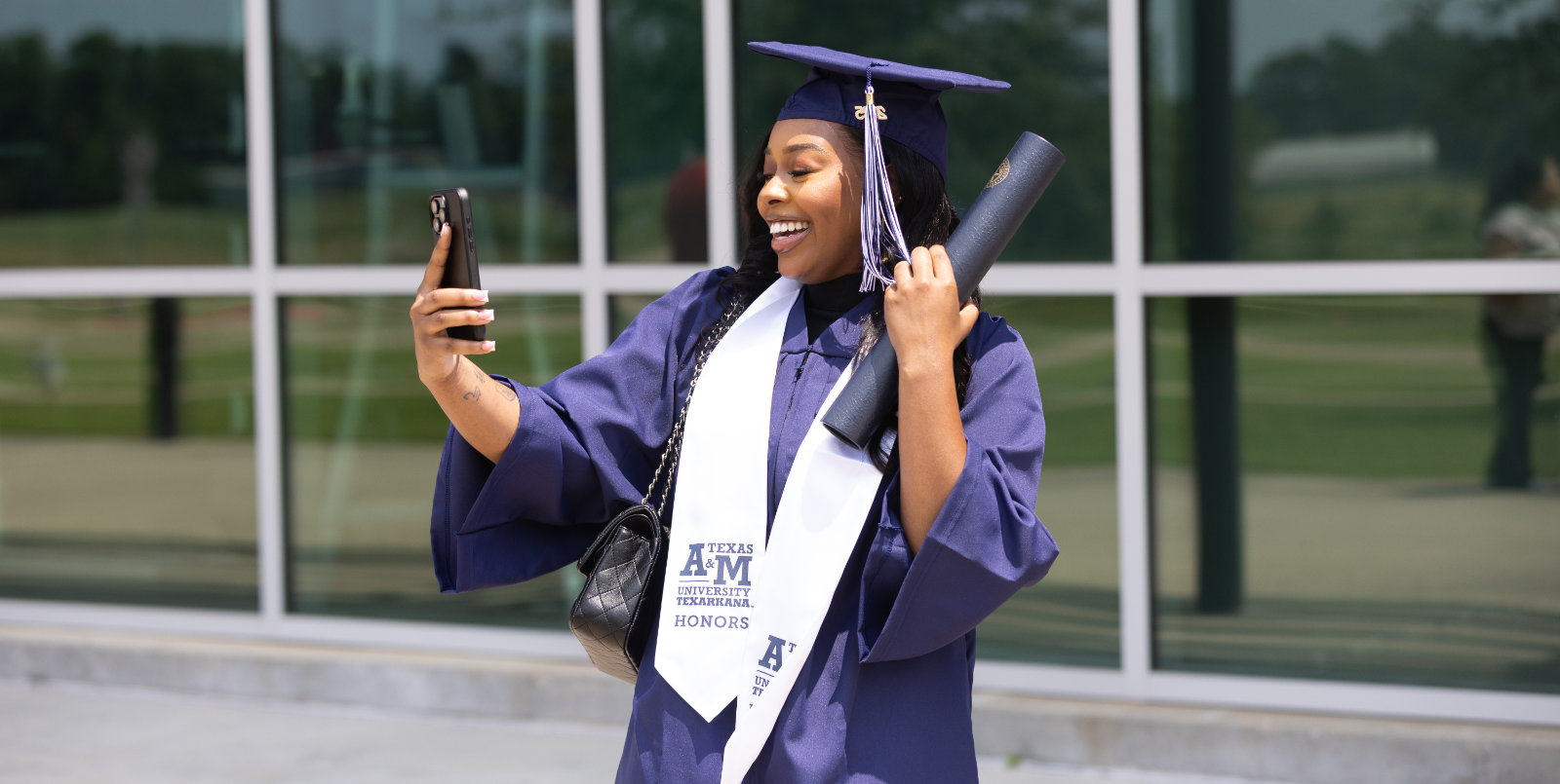A Texas A&M University Texarkana honors graduate celebrates with a selfie and diploma in hand